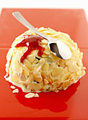 A vanilla ice cream bomb with slivered almonds and fruit sauce