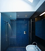 Bad mit blauen Mosaikfliesen an Wand und Boden mit verglastem Duschbereich
