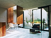 Living room with white chairs around an original dining table in front of a wall of windows