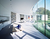 New home with a curved design with open living-dining area in front of a glass facade