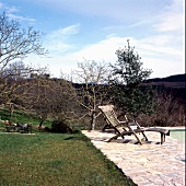 Verwitterter Holzliegestuhl am Poolrand in Mediterraner Landschaft