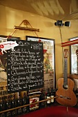 A menu on a blackboard next to a guitar in a Spanish bistro