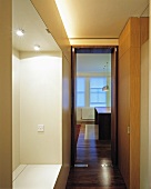 A classic-modern corridor with an illuminated cloakroom niche and a view through a glazed door into the kitchen