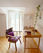 A rustic wooden armchair in front of a simple desk in an attic room