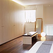 Black seat cushions on a bench in front of a built-in cupboard and a ball-shaped floor lamp