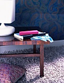 A white table lamp on a wooden side table on a fluffy lilac rug