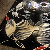 A coffee table, a floor vase and an animal figurine on a large black, patterned rug