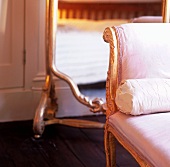 An antique chair with a pink satin cover