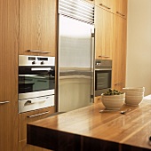 A fitted kitchen with wooden cupboards and a stainless steel fridge