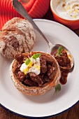 Beef goulash served in a hollowed out bread roll