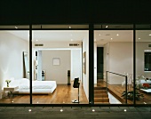 Terrasse mit Bodenstrahlern und Blick ins beleuchtete moderne Schlafzimmer und Wohnzimmer