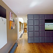 A television built into an upholstered partition wall with a view down a long corridor