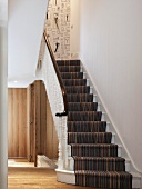 Staircase with striped runner and white turned balusters in modern foyer
