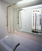 Bathroom seen in mirror over bathtub with designer tap fittings