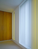 Ceiling-height, smooth, wooden double doors next to windows with vertical louver blinds