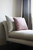 Scatter cushion with red leaf motif on white chaise longue with cushioned upholstery