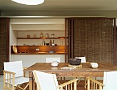 Antique wooden table and director's chairs in front of niche with small kitchen counter and bamboo sliding doors