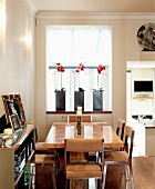 Three orchids in wall opening leading to conservatory behind caramel-coloured dining table with matching upholstered steel chairs