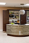 Curved kitchen island with glossy structured fronts in front of open refrigerator