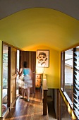 Eine Frau auf dem Flur mit Holzboden und gelben Wänden