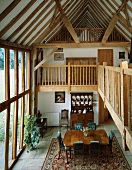 Open-plan house with dining area and views of gallery and rustic roof timbers