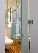Blick durch offene Tür in modernes Bad mit WC und auf Holzboden mit Intarsien