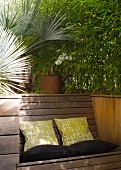Bambusbeet mit integrierter Holzbank und Kissen auf Terrasse