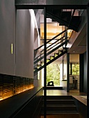Open-plan stairwell with integrated, backlit sideboard in contemporary house