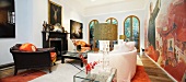 Antique leather armchair and light sofa in front of mural in living room of villa