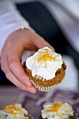 A hand holding a carrot muffin