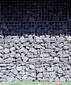 Gabion fence of stacked stone in wire cages