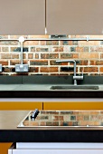 Ausschnitt einer modernen Küchenzeile vor alter Ziegelwand mit Elektroleitung