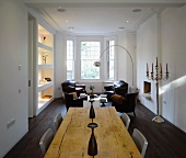 Open-plan living with rustic wooden table and antique leather armchairs in bay window