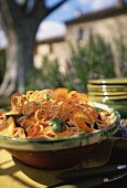 Spaghettoni with carrots and oranges on a table in the open air