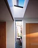 Fitted wardrobe with wooden door in niche of foyer with skylight and floor to ceiling window