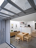 Blick durch offene Terrassenschiebetür auf Essplatz mit Klassikerstühlen und moderne Küche