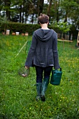 A woman with a watering can and an egg basket