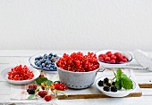 Various berries on small plates and in a colander