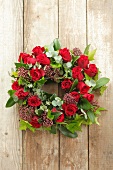 A bunch of eucalyptus, roses, ivy and skimmia hanging on a wooden wall