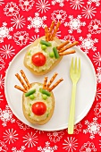 Potatoes filled with mashed potatoes and decorated with peas, cherry tomatoes and pretzel sticks to look like reindeer