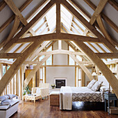 Bedroom in the attic with exposed wooden beams and skylights