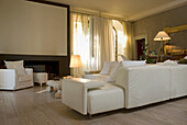 Living room with fireplace, white leather couch and light-coloured wooden floor