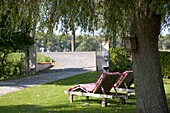 Liegestühle und Vogelhaus im sonnigen Garten