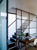 Antique desk with white shell chair in front of staircase in contemporary house