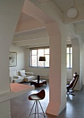 View of barstool and white sofa combination through open column structure in loft-style interior