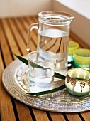 A jug of water and a glass on a sliver tray