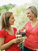 Two women with glasses of wine on a wooden bridge