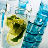 A glass jug of water with limes