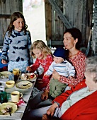 Two women and three children eating cake in a barn