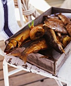 Various types of smoked fish in a wooden crate
